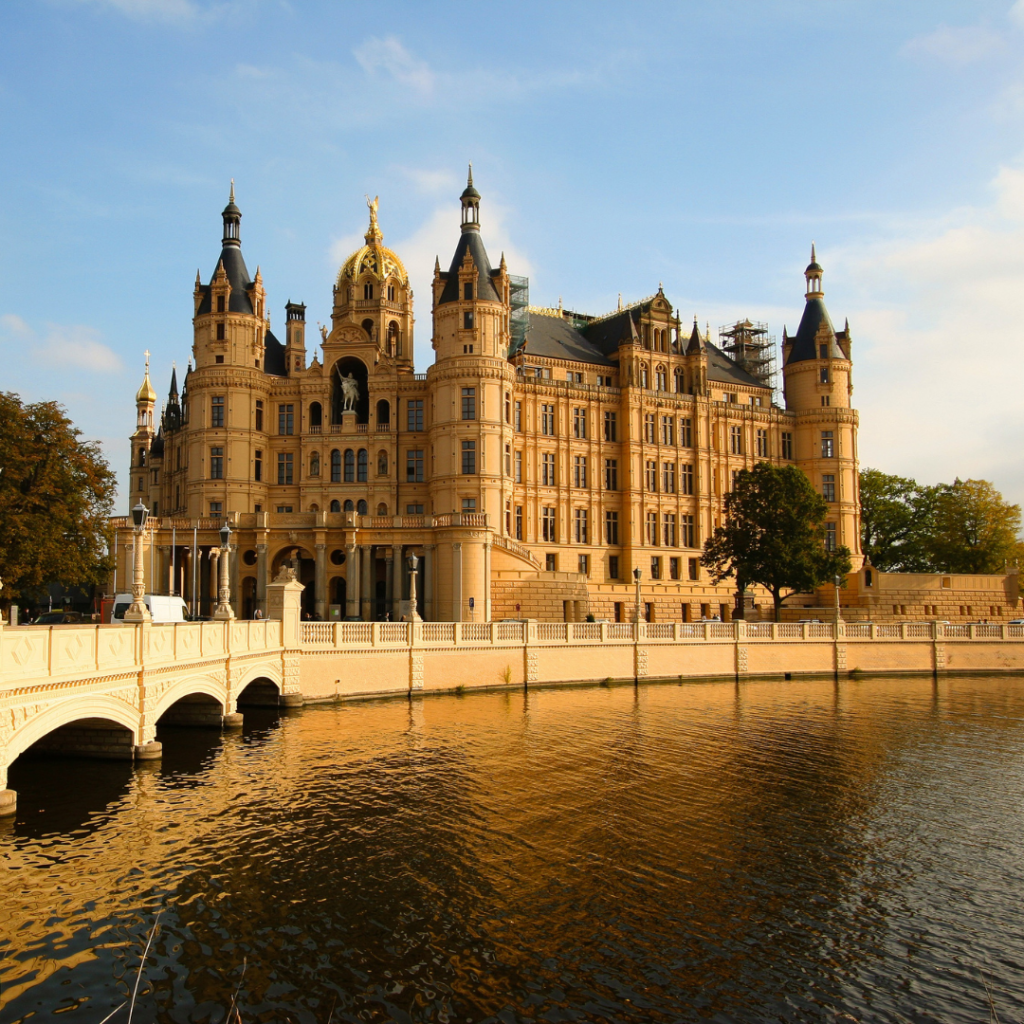 Das Schweriner Schloss in goldgelbem Sonnenlicht, umgeben vom See mit dem Hinweis Gewerbeanmeldung in Mecklenburg-Vorpommern