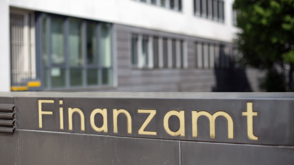 Close up of a sign saying "Finanzamt" with a Finanzamt building in the background