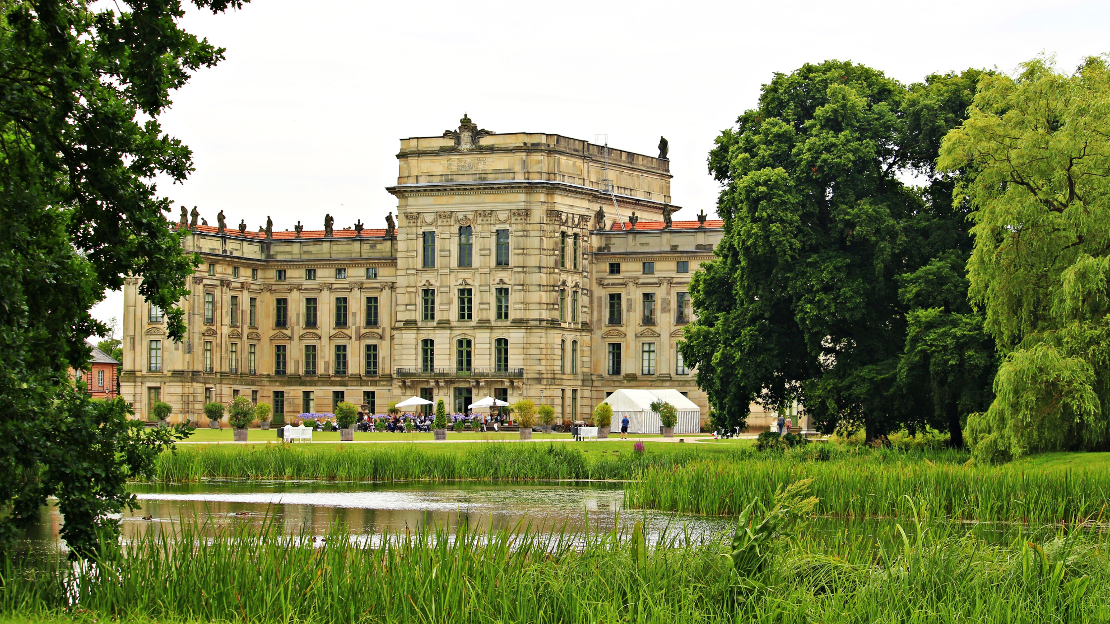 Ludwigsluster Schloss mit Teich, Bäumen und Schilf im Vordergrund