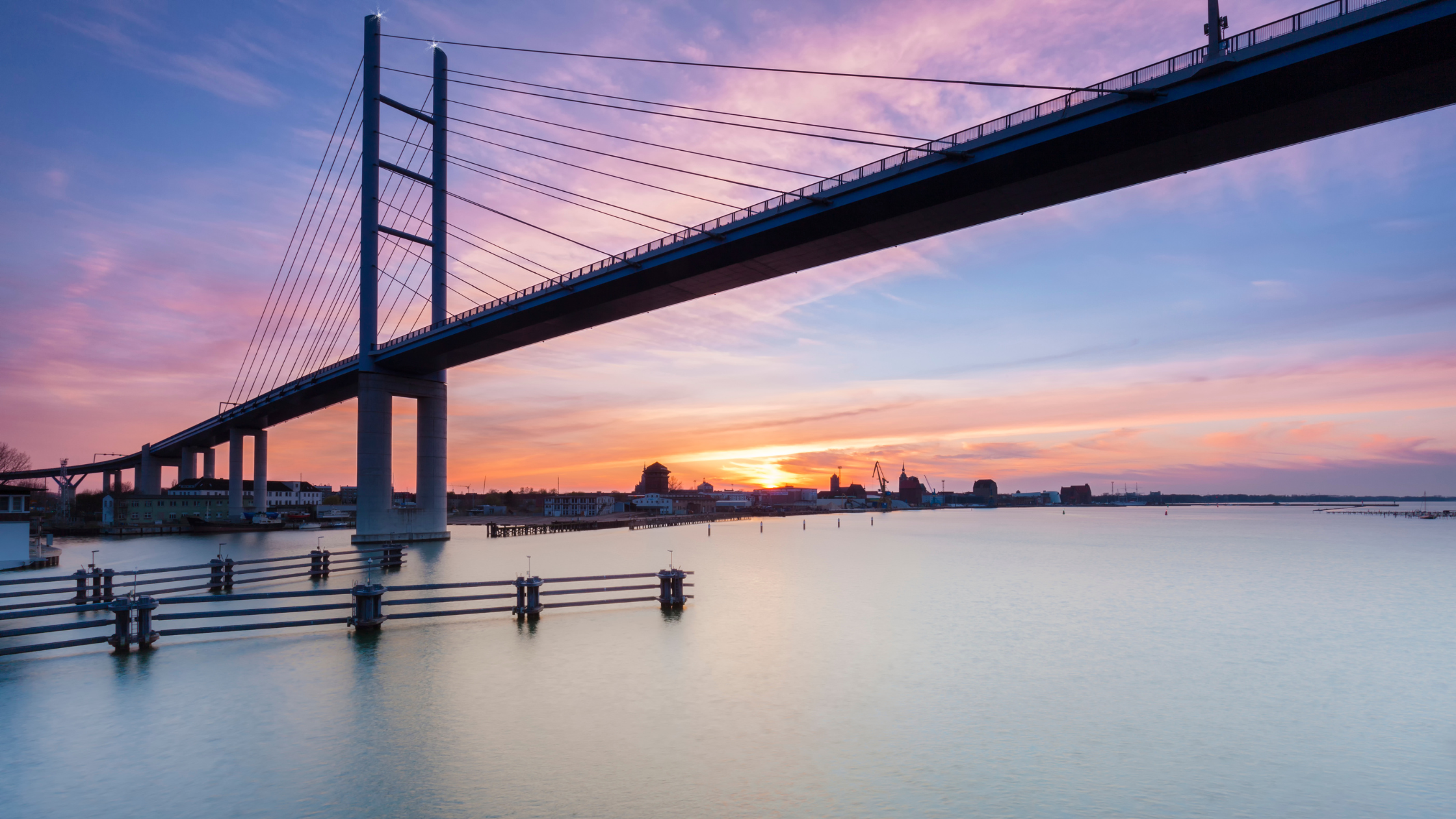 Rügenbrücke von unten mit Blick auf die Stadtsilhouette von Stralsund im Sonnenuntergang