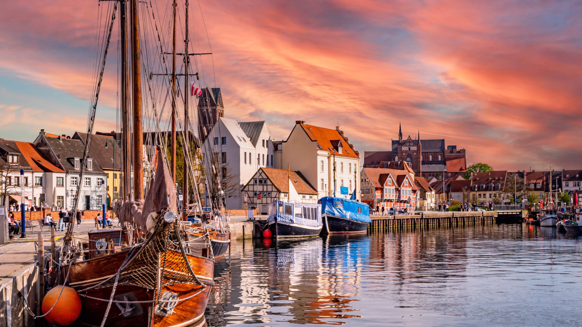 Historisches Segelboot und andere Boote im Alten Hafen von Wismar bei Sonnenuntergang