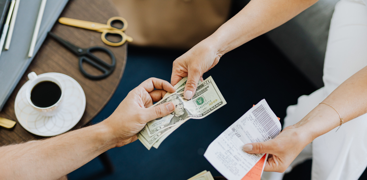 Symbolbild für ordnungsgemäße Kassenführung Person bezahlt mit Bargeld und erhält von einer anderen Person den Kassenbeleg