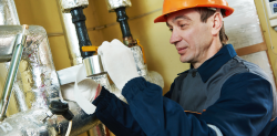 Symbolbild für Energieeffizienz: Handwerker isoliert Leitungsrohre