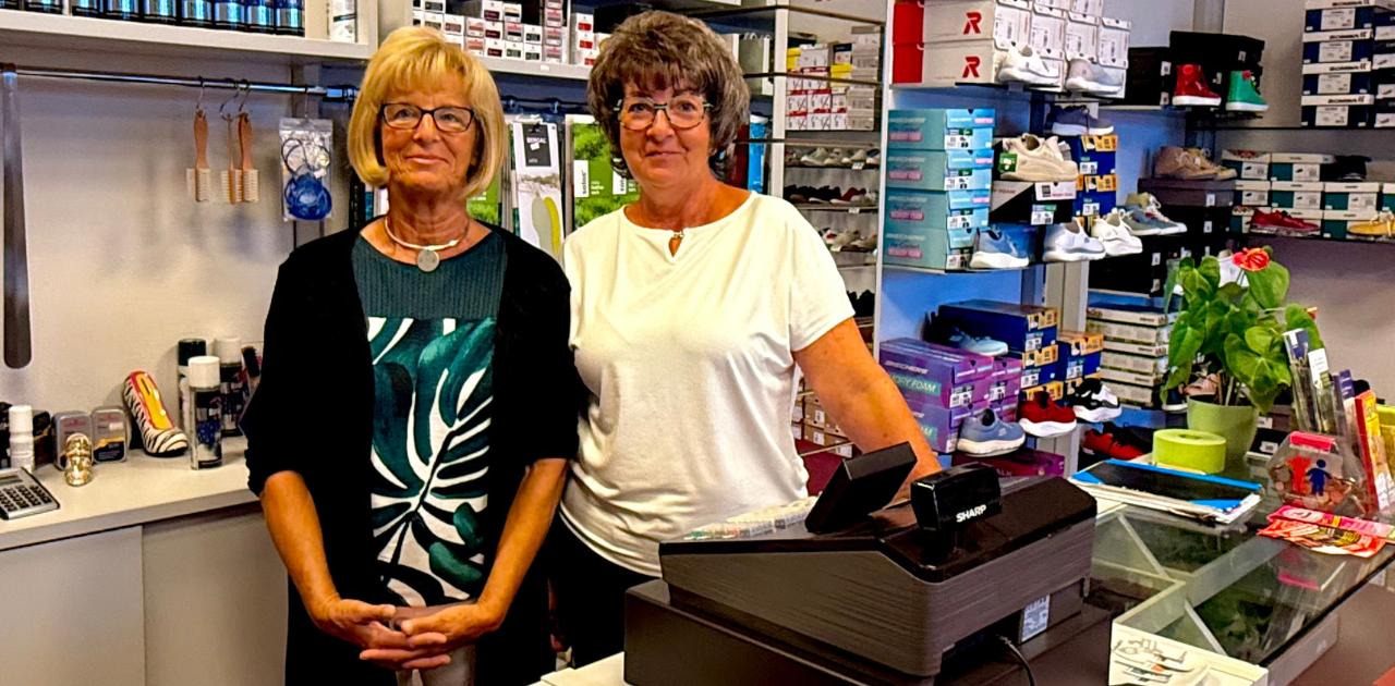 Marianne Fraß und Simone Reinoldsmann stehen nebeneinander im Schuhgeschäft, lächeln in die Kamera; im Hintergrund sind Schuhregale sichtbar.