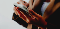 Symbolbild für Social Commerce: Person tippt auf ein Smartphone, dass sie in der Hand hält