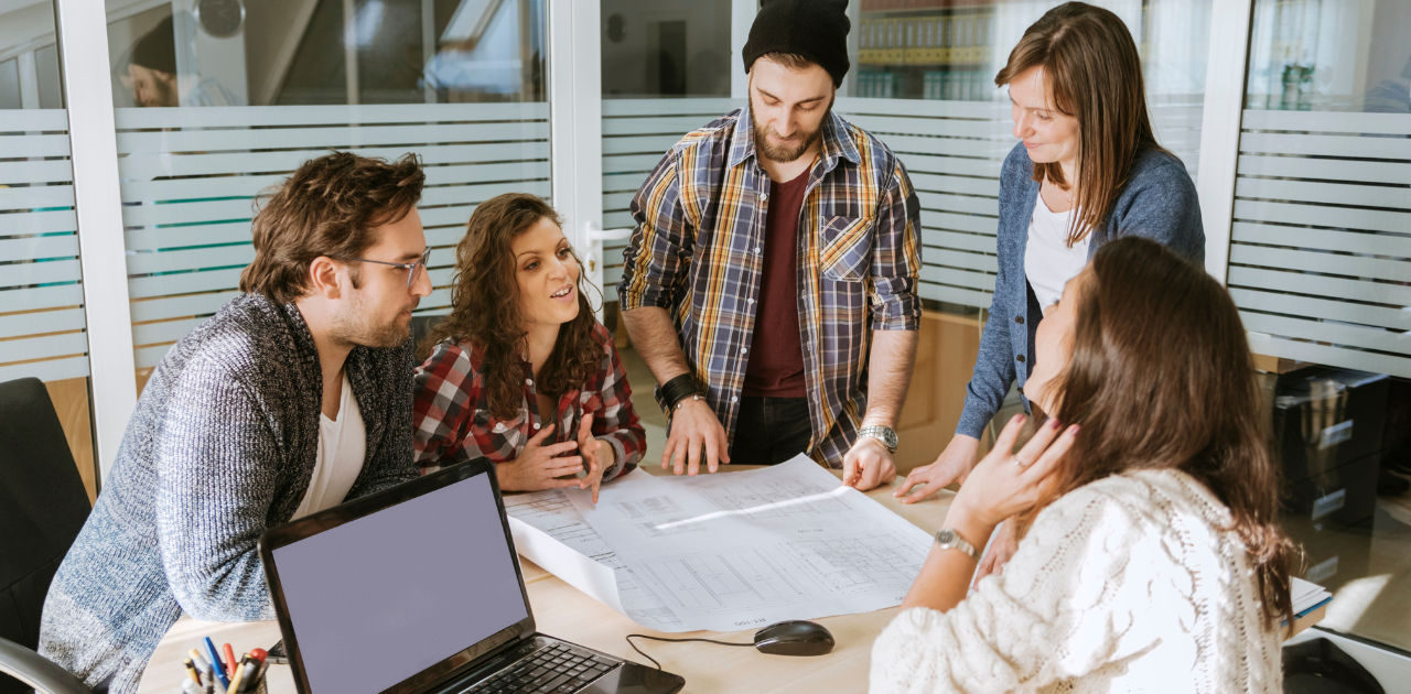 Fünf Personen in einem modernen Büro, die gemeinsam an einem Start-up arbeiten und vom ERP-Gründerkredit – StartGeld profitieren