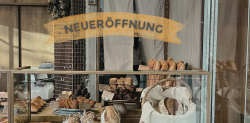 Symbolbild für Gründungen: Blick durch ein Fenster in einen Bäckerladen, auf der Scheibe sieht man den Schriftzug "NEUERÖFFNUNG"