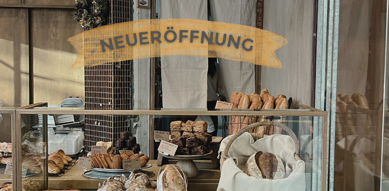 Symbolbild für Gründungen: Blick durch ein Fenster in einen Bäckerladen, auf der Scheibe sieht man den Schriftzug "NEUERÖFFNUNG"