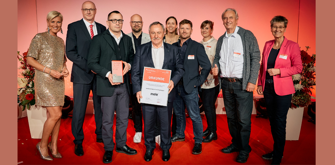 Gruppenfoto der mele Unternehmensgruppe bei der Preisverleihung des Unternehmer-Preises 2025 während des OSV-Unternehmerkonvents in Potsdam. Personen stehen auf rotem Teppich vor rotem Hintergrund, halten Urkunde und Trophäe.
