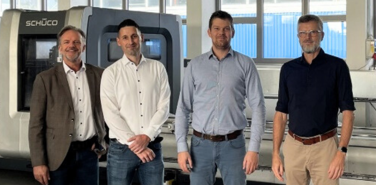 Vier Personen stehen vor einer Schüco-Maschine im Produktionsbereich von Warnow Metall, Symbol für die erfolgreiche Unternehmensnachfolge und Zusammenarbeit mit Nachfolgezentrale MV und BMV.