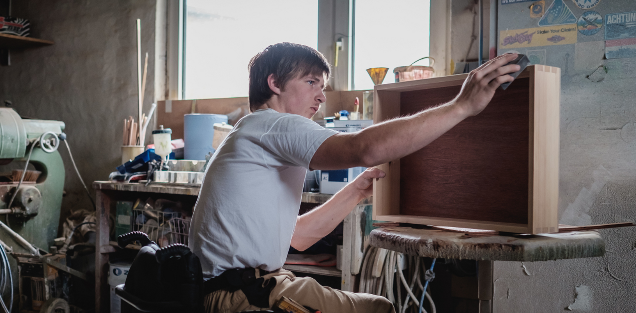 erson im Rollstuhl arbeitet in einer Werkstatt an einer Schublade
