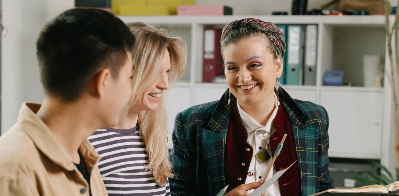 3 Personen unterhalten sich, sie stehen dabei vor einem Büroregal