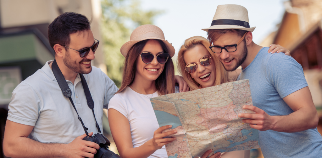 Symbolbild für Wettbewerb Deutscher Tourismuspreis: vier Personen stehen draußen und schauen auf einen Straßenkarte