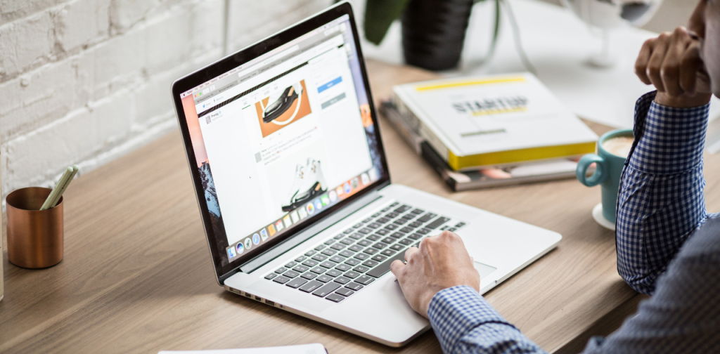 eine Person sitzt vor einem aufgeklappten Laptop