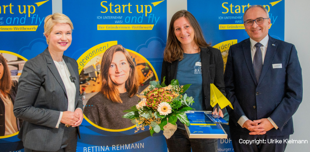 links Frauenhand mit einem Papierflieger, rechts Informationen zum Wettbewerb Start up and fly