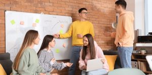 Gründer und Team arbeiten gemeinsam an einem Whiteboard. Der Rollenwechsel vom Gründer zur Führungskraft erfordert Kommunikation, Vertrauen und Mitarbeiterführung.