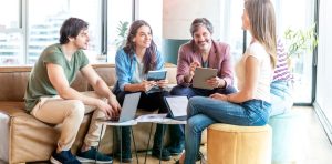 Team bespricht gemeinsam ein Projekt in einem modernen Büro und arbeitet mit Laptops und Tablets zusammen.