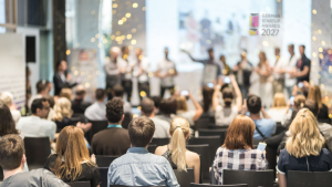 Publikum bei einer Startup-Veranstaltung mit Bühne und projiziertem Logo der German Startup Awards 2027 im Hintergrund.