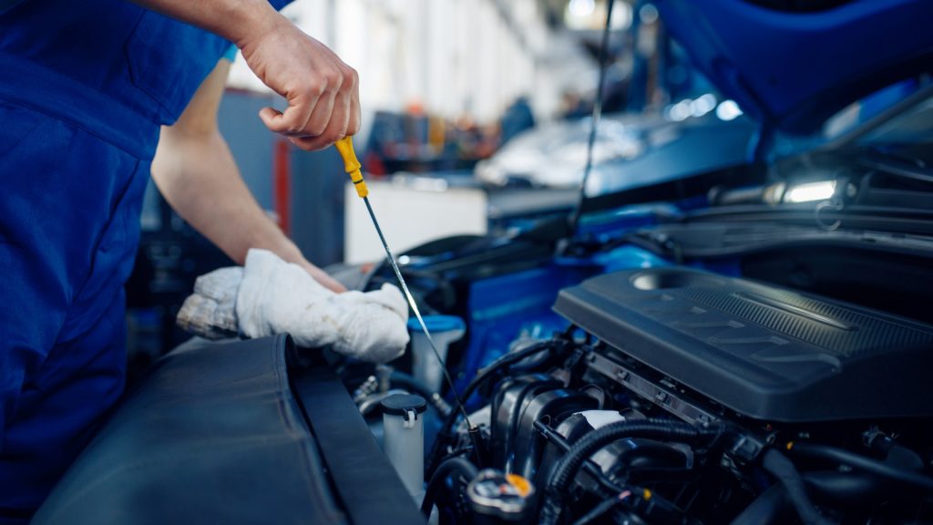 eine Person hat eine Motorhaube geöffnet und arbeitet am Motor