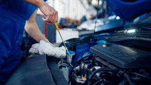 eine Person hat eine Motorhaube geöffnet und arbeitet am Motor