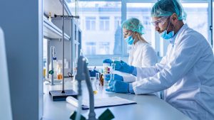Zwei Personen arbeiten an einem Labortisch, sie tragen Mundschutz