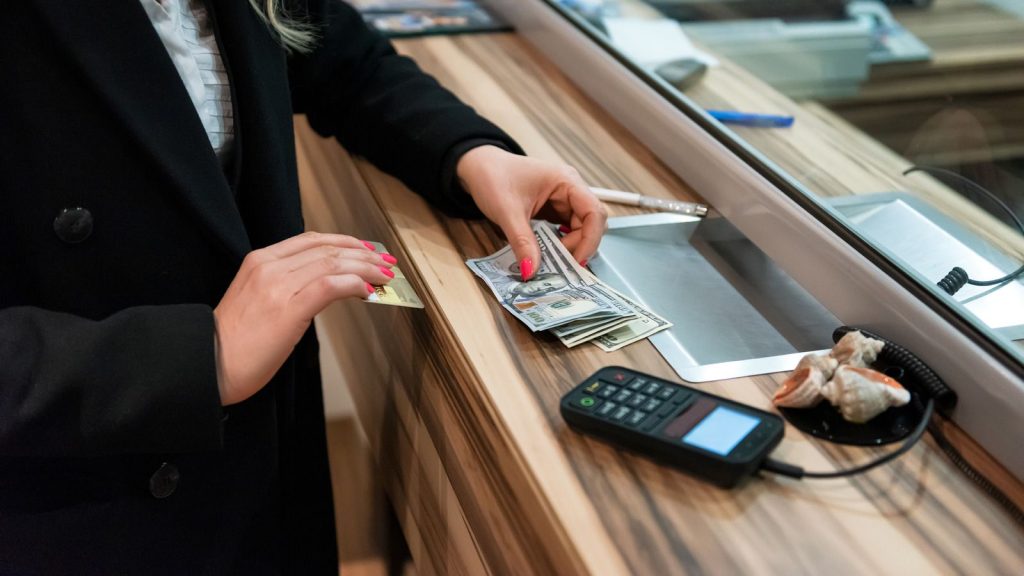 Eine Person steht am Bankschalter und zahlt Geld ein